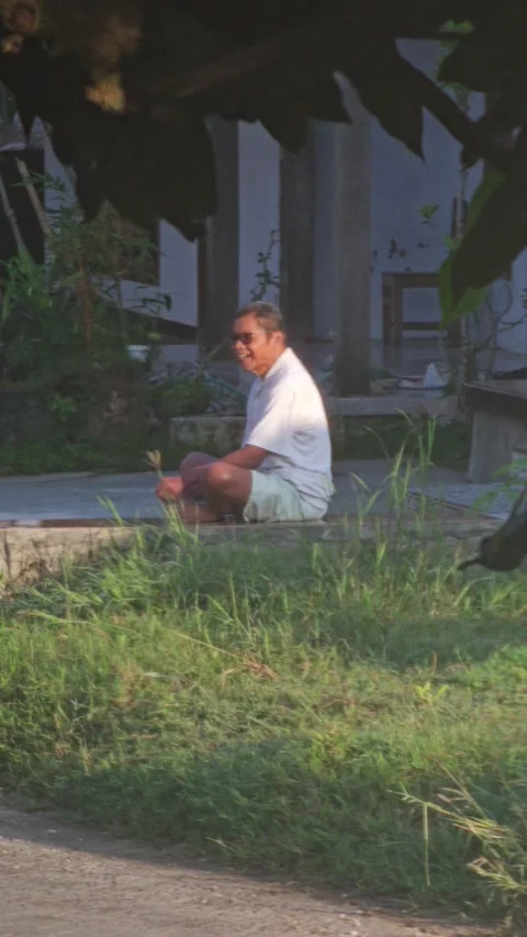 Asian Man Sitting Cross Legged Outdoors Smiling Wearing Sunglasses Stock Footage 339916673