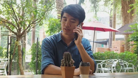 Asian man sitting  drinking take away coffee and calling on phone Stock Footage 118362718