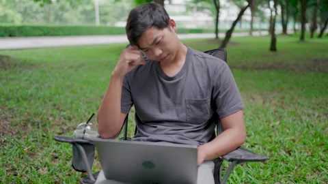 Asian man sitting stressed from work on chair in front of laptop computer in nat Stock Footage 283186489