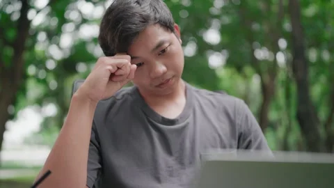 Asian man sitting stressed from work in chair in front of computer Stock Footage 283186498