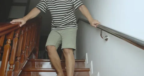 Asian man slowly going down staircase at home. Stock Footage 238930795