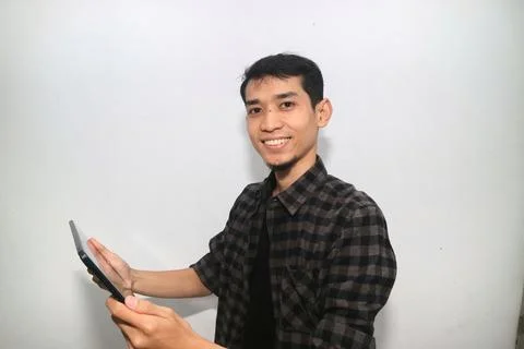 Asian man smiling at the camera when working using mobile tablet gadget 写真素材