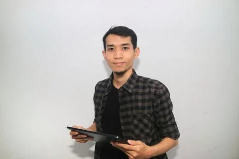 Asian man smiling at the camera when working using mobile tablet gadget 写真素材