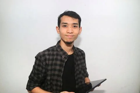 Asian man smiling at the camera when working using mobile tablet gadget 写真素材