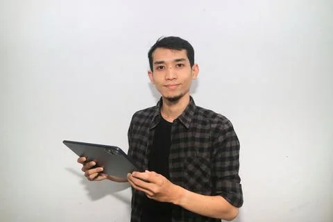 Asian man smiling at the camera when working using mobile tablet gadget 写真素材