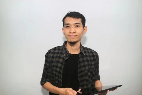 Asian man smiling at the camera when working using mobile tablet gadget 写真素材
