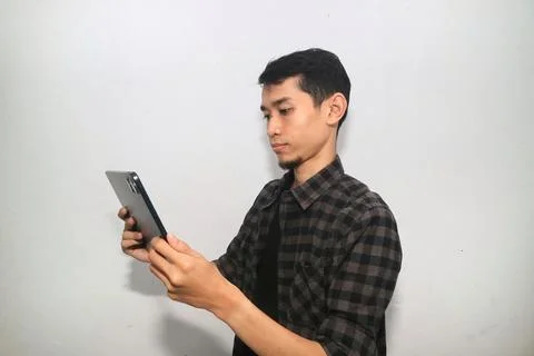 Asian man smiling at the camera when working using mobile tablet gadget 写真素材