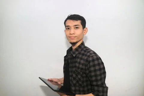 Asian man smiling at the camera when working using mobile tablet gadget 写真素材