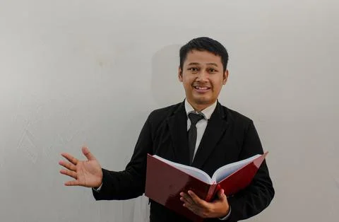 Asian man smiling at the camera while holding a book Stock Photos