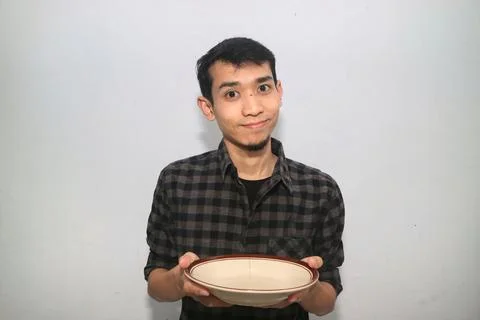 Asian man smiling at the camera while holding an empty dining plate Stock Photos