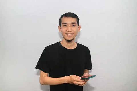 Asian man smiling happy while holding mobile phone Stock Photos