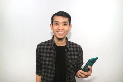 Asian man smiling happy while holding mobile phone Foto stock