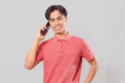 Asian man smiling looking at camera while answering call using mobile phone Stock Photos