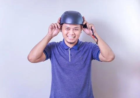 An asian man is smiling while adjusting his helmet, ready for a bike ride. Stock Photos