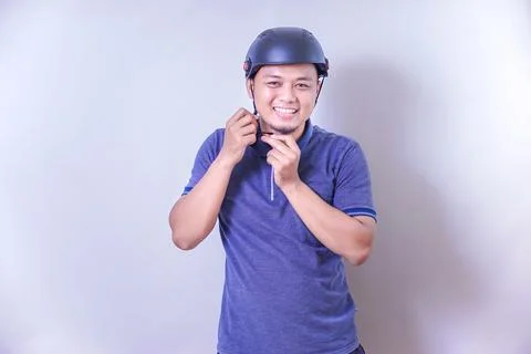 An asian man is smiling while adjusting his helmet, ready for a bike ride. Stock Photos