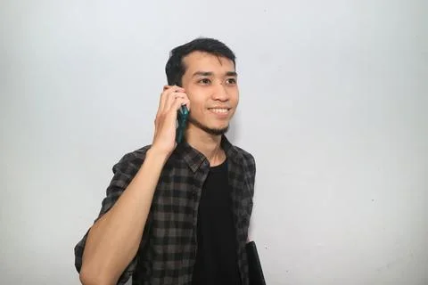 Asian man smiling while answering a phone call Stock Photos