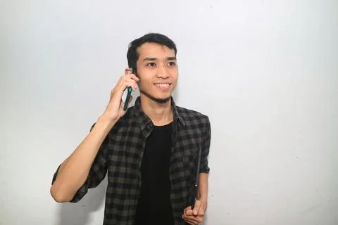 Asian man smiling while answering a phone call Foto stock