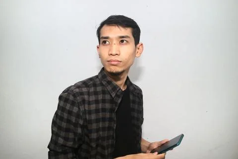 Asian Man smiling while looking at smartphone, candid expression of happine.. Stock Photos