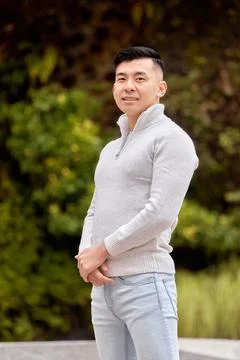 Asian man smiling while standing outdoors in a park. Fotos Stock