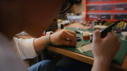Asian Man Soldering Electronic Components on Circuit Board Stock Footage 338422525
