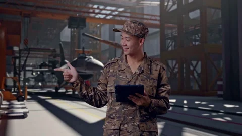 Asian Man Soldier Using A Tablet And Pointing To Side in Aircraft Hangar Stock Footage 313428567