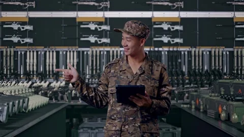 Asian Man Soldier Using A Tablet And Pointing To Side In Military Armory Stock Footage 313739560