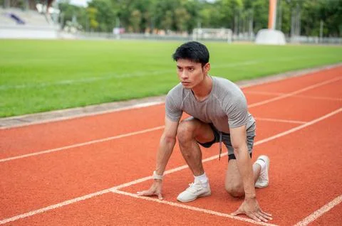 Asian man sprinter crouching getting ready at the start line of running tra.. Stock Photos