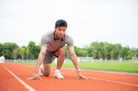 Asian man sprinter focused while crouching in start position ready to run o.. Stock Photos