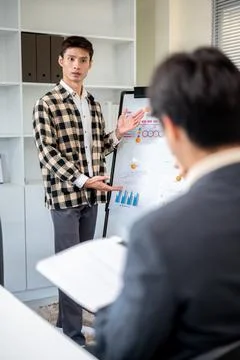 Asian man standing and doing work presentation with a board to businessman .. Stock Photos