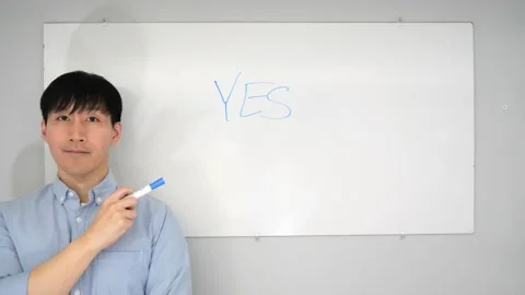 Asian man standing in front of a white board writing yes no or mabye Vidéo 263858688