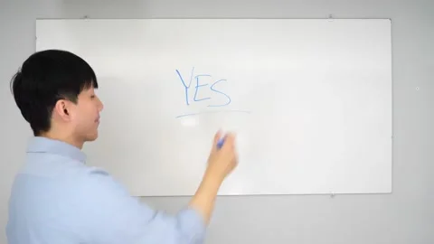 Asian man standing in front of a white board writing yes no or mabye Vidéo 263858736
