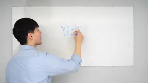 Asian man standing in front of a white board writing yes no or mabye Vidéo 263858744