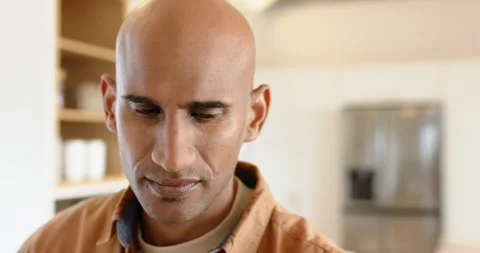 Asian man standing in home kitchen shifting gaze upward from shelves making eye Stock Footage 339591070