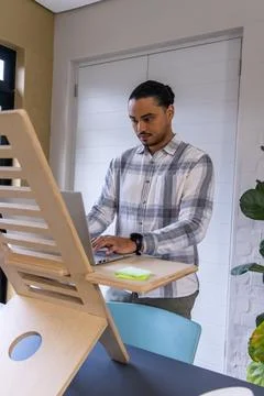 Asian man standing at home using laptop on wooden riser with green sticky notes 写真素材