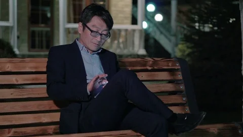 Asian man in a suit writes a text message and smiles. The evening Stock Footage 75811961