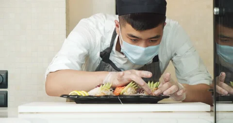 Asian man sushi chef serving sashimi with fresh vegetables and fish on a plate Stock Footage 135584838
