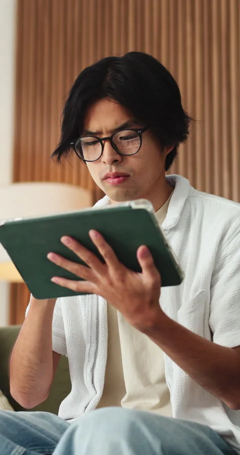 Asian man, tablet and thinking on sofa in home with application for newsletter Stock Footage 331652440