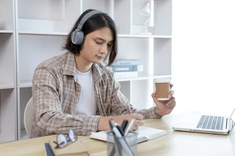 Asian man taking notes in notebook while studying online in laptop at home, V Stock Photos