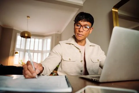 Asian man taking notes while on laptop Stock Photos