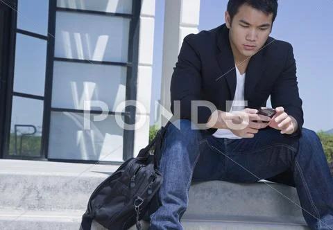 Asian Man Text Messaging With Cell Phone