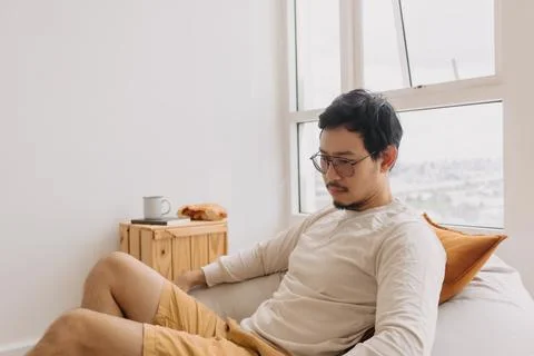 Asian man thinking and missing sits on bean bag and relaxed in weekend Stock Photos