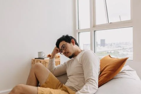 Asian man thinking and missing sits on bean bag and relaxed in weekend Stock Photos