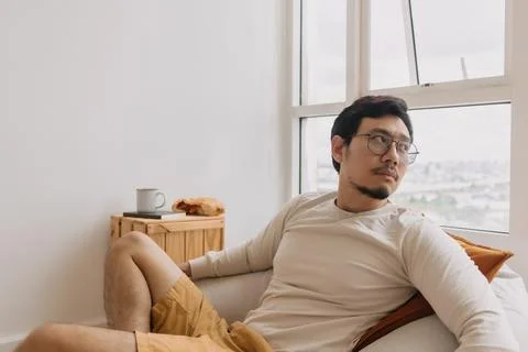 Asian man thinking and missing sits on bean bag and relaxed in weekend Stock Photos
