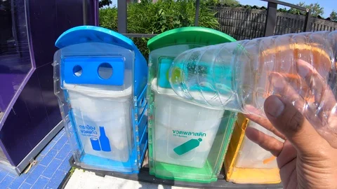 Asian man throwing plastic bottle into blue trash can. Stock Footage 97457538
