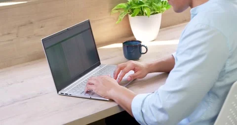 Asian man typing spreadsheet on laptop at desk, pausing work, sipping from blue Stock-Footage 341952922