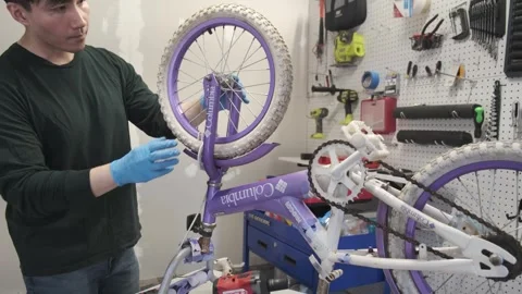 Asian man uses tools to fix wheel of a bike San Francisco CA USA July 15 2025 Stock Footage 313171563