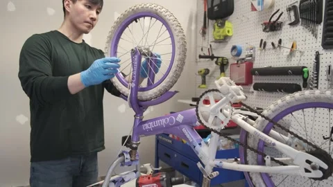 Asian man uses tools to fix wheel of a bike San Francisco CA USA July 15 2025 Stock Footage 313171566