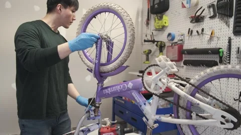 Asian man uses tools to fix wheel of a bike San Francisco CA USA July 15 2025 Stock Footage 313171567