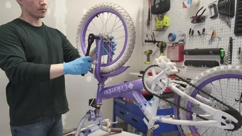 Asian man uses tools to fix wheel of a bike San Francisco CA USA July 15 2025 Stock Footage 313171569