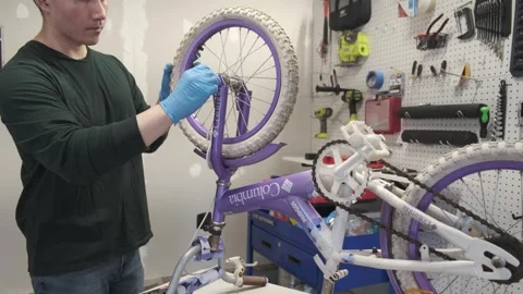 Asian man uses tools to fix wheel of a bike San Francisco CA USA July 15 2025 Stock Footage 313171570